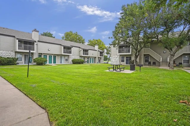 Exterior view of a multi-building apartment community with a grassy courtyard and pathways.