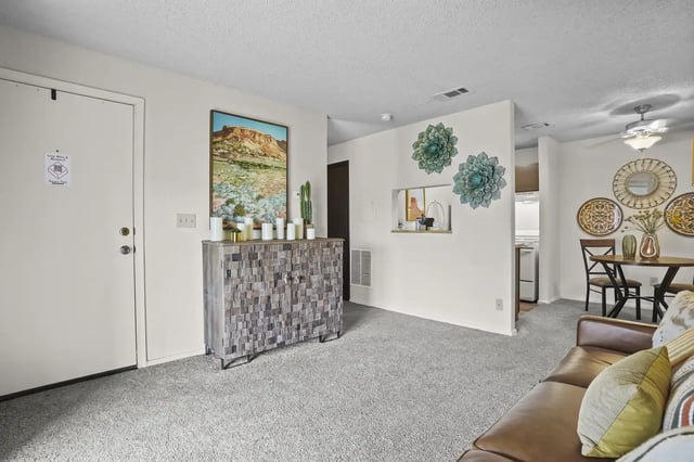 Interior community lounge with a leather sofa, wall art, and a small dining area.