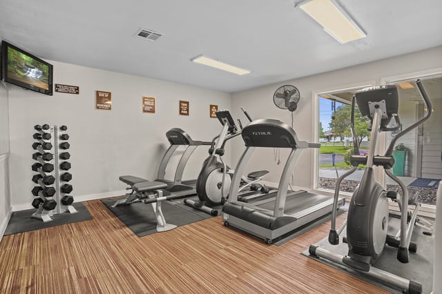 Fitness center with treadmills, elliptical, dumbbells, and TV.