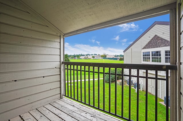 View from balcony of a grassy field and building exterior.