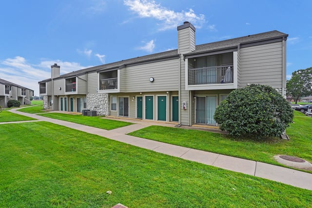 Exterior of apartment buildings with green lawns and walkways.