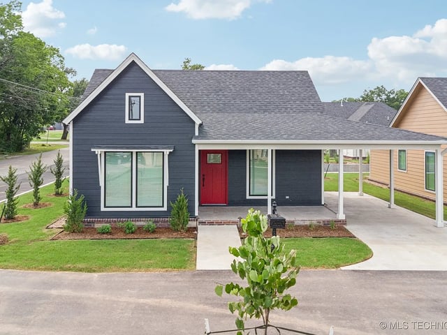 Exterior view of a modern house with a covered porch and landscaped yard.