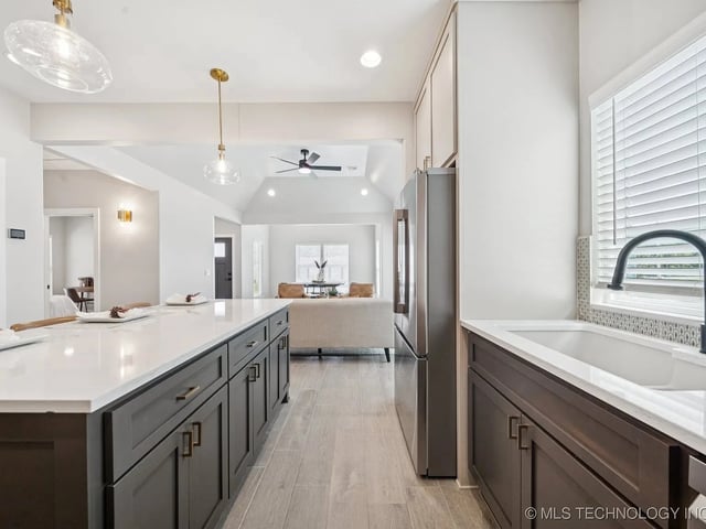 Modern kitchen featuring a large island with dark cabinetry and stainless steel appliances.