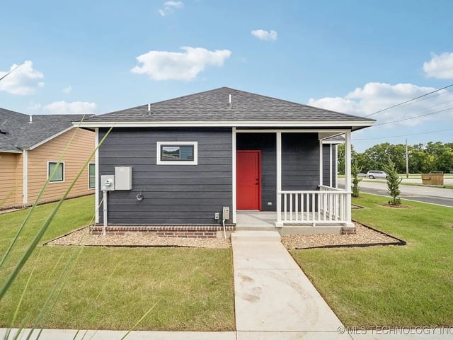 Exterior view of a modern single-family house with a red front door and landscaped yard