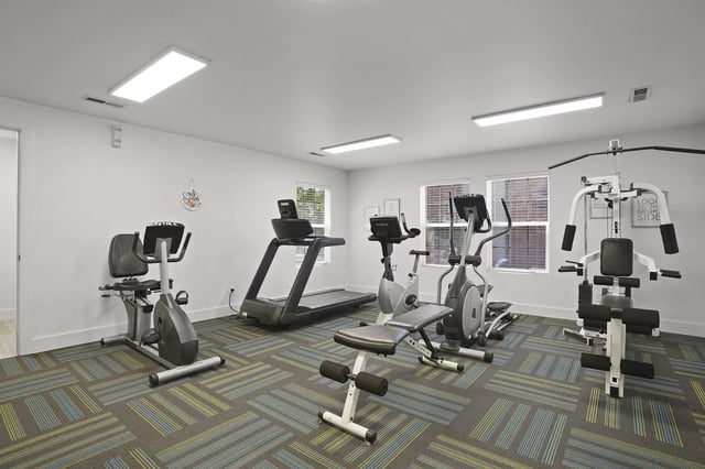 Fitness center with cardio machines, free weights, and a TV.