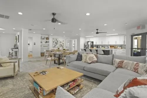 Spacious lounge area with a large sectional sofa, coffee table, dining table, and a full kitchen.