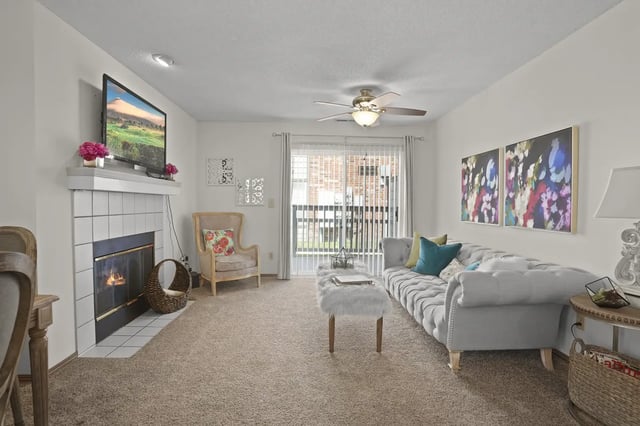 Living room with a fireplace, TV, sofa, armchair, and decorative art.