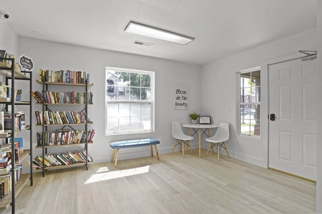 A room with a bookshelf, a bench, and a table with chairs.