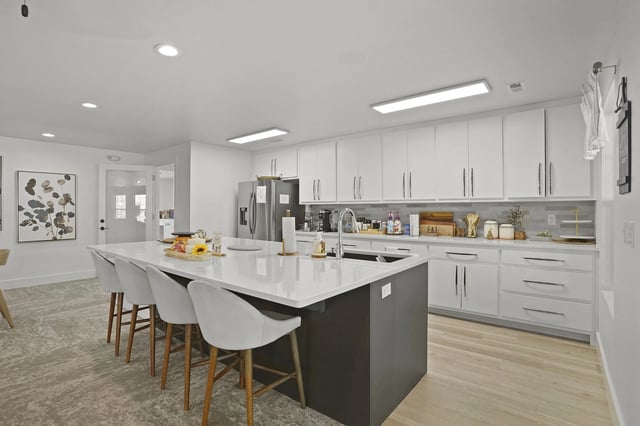 A modern kitchen with a large island and white cabinets.
