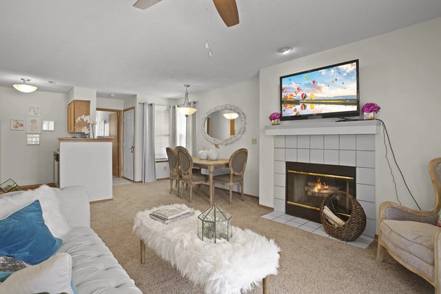 A living room with a fireplace and a television mounted above it.