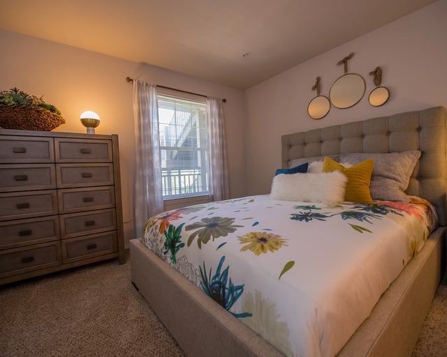 A bedroom with a large bed and a window with curtains.