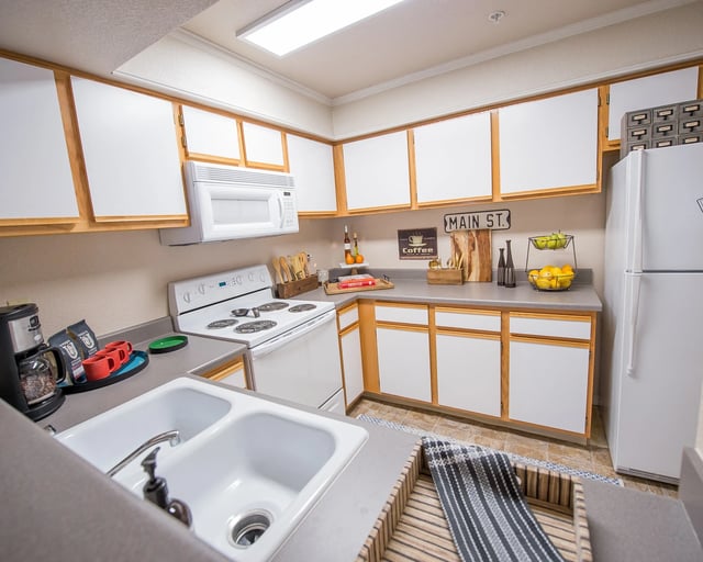 A kitchen with white cabinets and a white refrigerator.