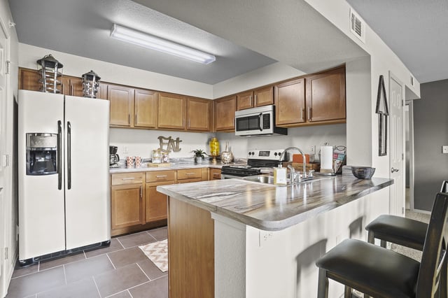 A kitchen with a white refrigerator and wooden cabinets.