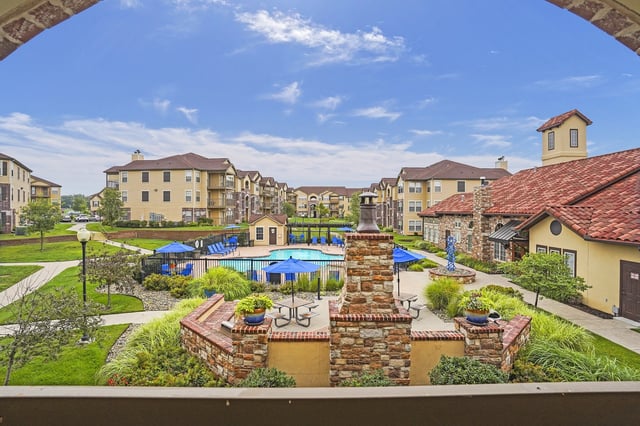 Apartment complex with a swimming pool and surrounding buildings.