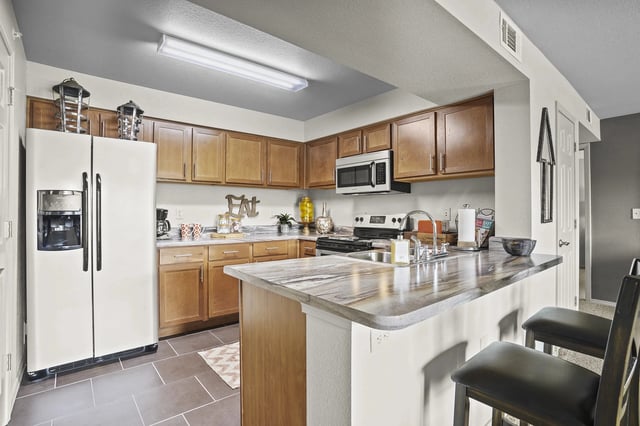 A kitchen with a white refrigerator and wooden cabinets.