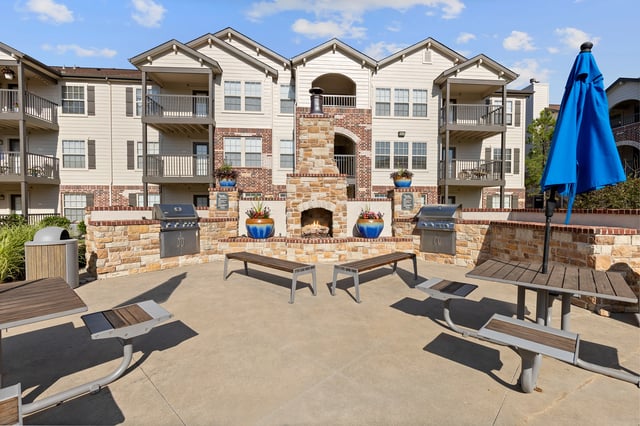 Outdoor grilling and fireplace area with seating at The Overlook at Overland Park.