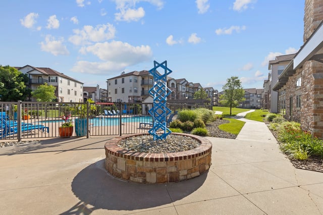 Outdoor swimming pool area with lounge chairs and a decorative sculpture.