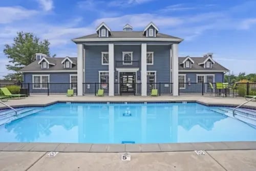 Blue multifamily building with white columns and a large blue swimming pool in front.