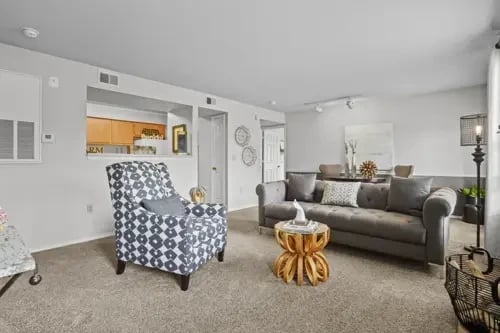 Living room with a gray tufted sofa, accent chair, and pass-through to the kitchen.