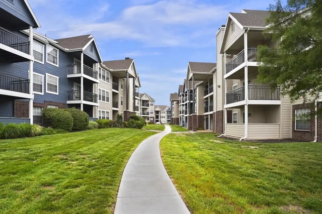 Exterior view of a multi-building apartment complex with balconies and a curved walkway.