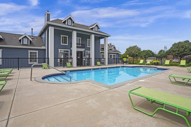 Outdoor pool area with blue water, lime-green lounge chairs, and a fenced courtyard.