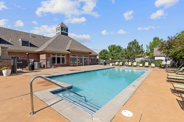 Swimming pool with lounge chairs and a building in the background.