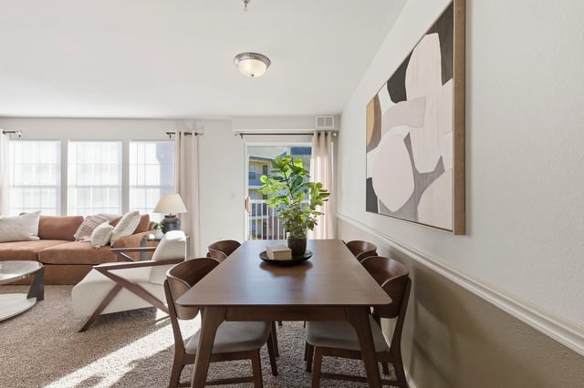 Dining table with chairs in a sunlit living room.