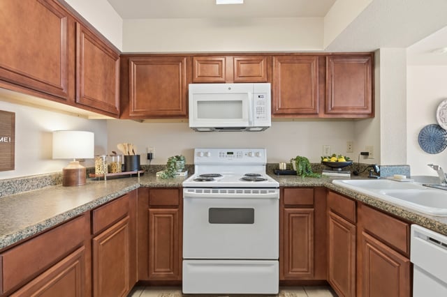Kitchen with wooden cabinets, white appliances, and granite countertops.