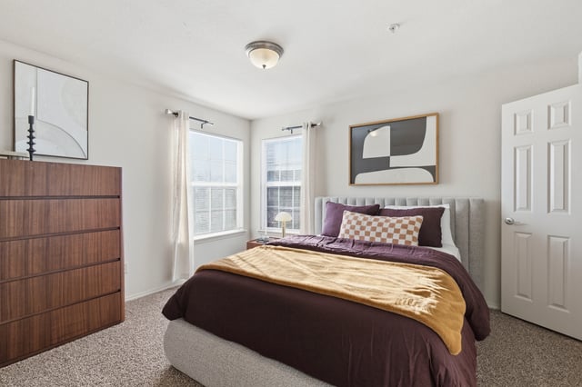Bedroom with a bed, dresser, and artwork.