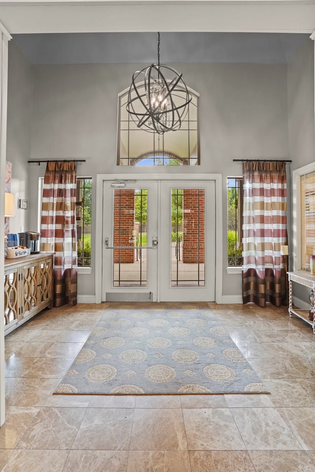 Double doors with windows in an entryway with a chandelier above.