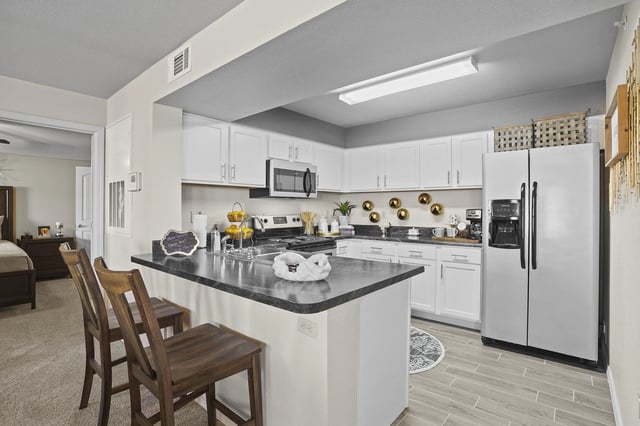 A kitchen with a black counter top and white cabinets.