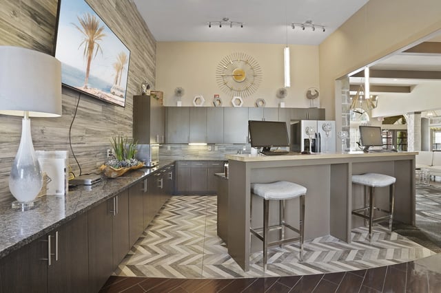 Modern leasing office with computers, kitchen counter, and seating area.