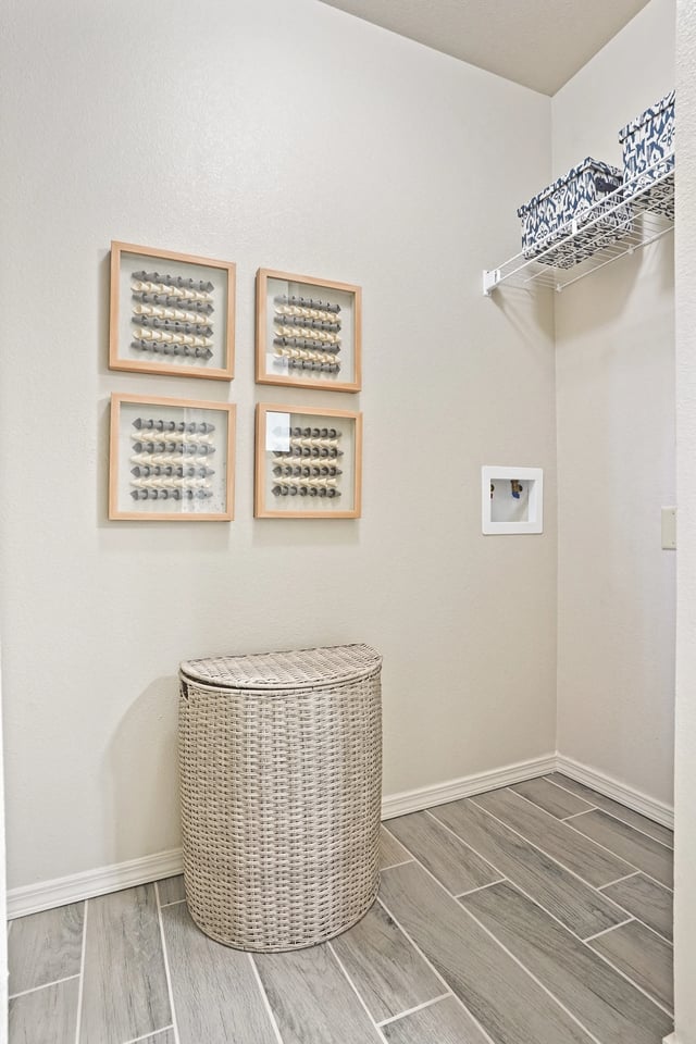 Laundry room with washer hookups, decorative wall art, and a wicker hamper.