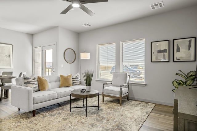 Modern living room with a white sofa, armchair, coffee table, and large windows.