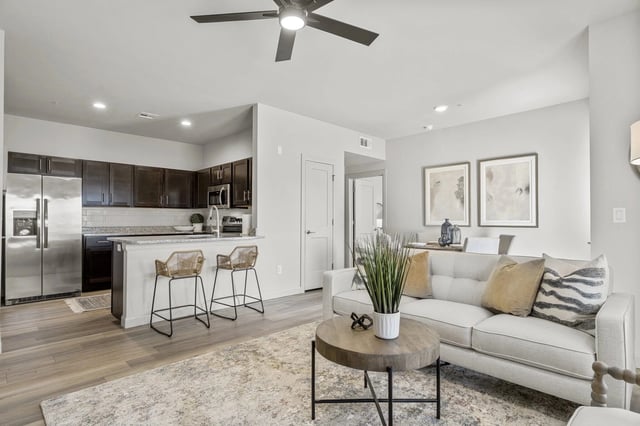 Open-concept living area with kitchen island, bar stools, and stainless steel appliances.
