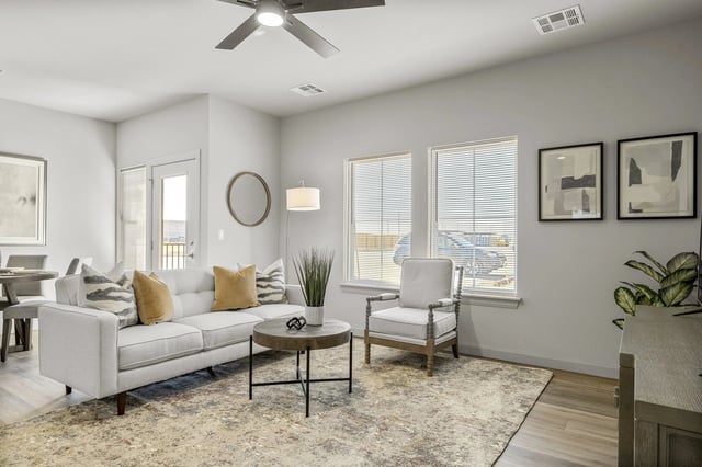 Bright apartment living room with a white sofa, armchair, rug, and large windows.