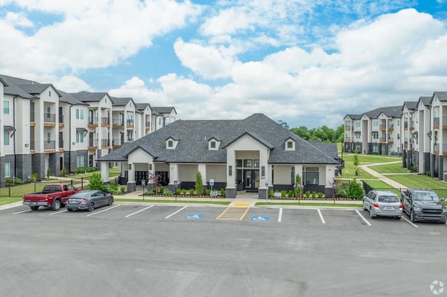 Exterior view of a modern apartment community with a central leasing center and surrounding buildings.