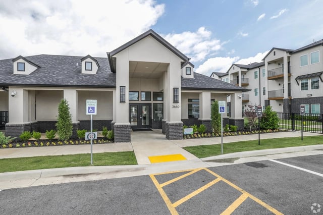 Exterior view of a modern apartment community entrance with a covered entry and landscaping.