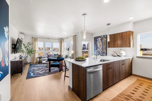 Open-concept living room and kitchen in a modern apartment with city-view windows.