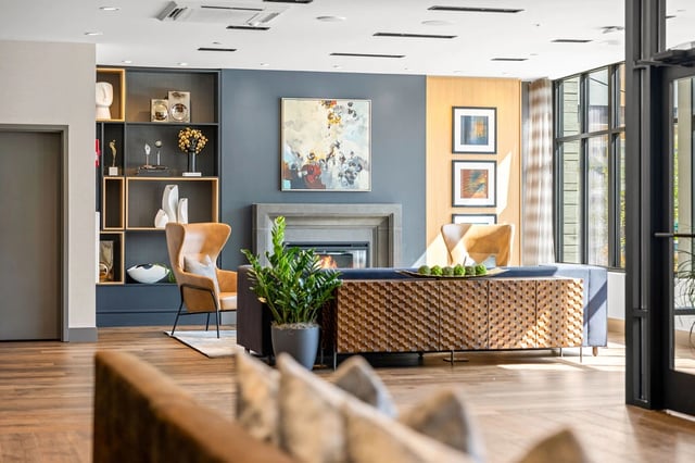 Modern apartment community lobby with blue accent wall, fireplace, shelves, and seating.