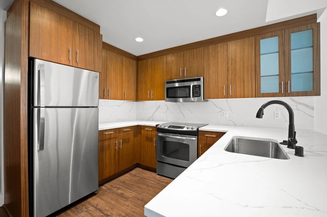 Modern kitchen with stainless steel appliances, wood cabinets, and quartz countertops.