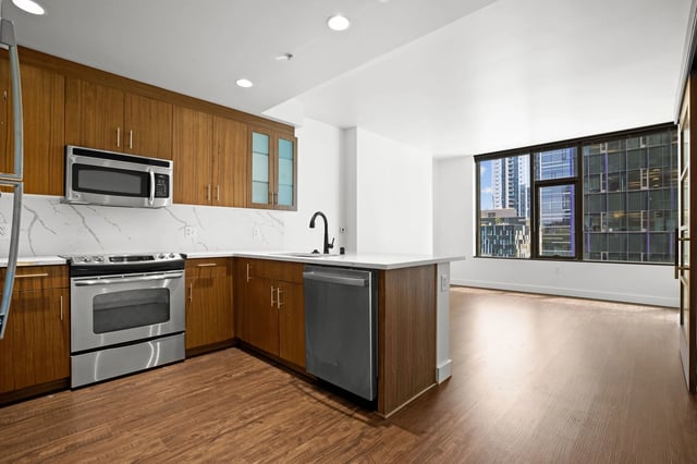 Modern kitchen with stainless steel appliances, granite countertops, and wood cabinets.
