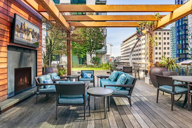 Rooftop lounge with fireplace, seating areas, and city views.