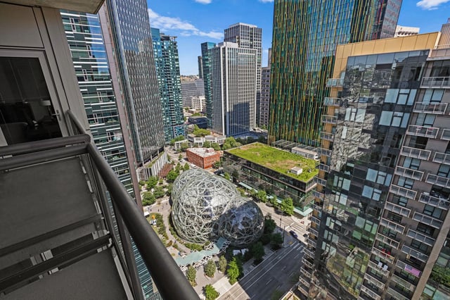 View of downtown Seattle from a balcony, featuring modern skyscrapers and the Amazon Spheres.