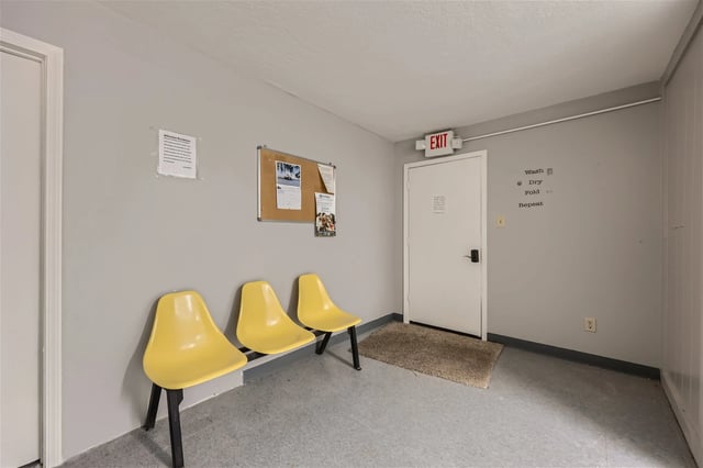 Laundry room waiting area with yellow chairs and an exit sign.