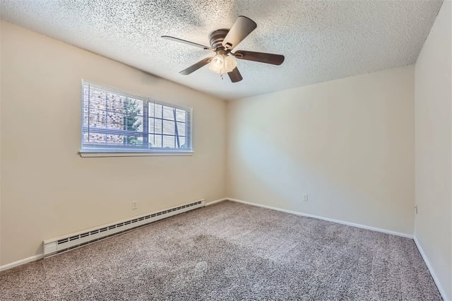 Bedroom with beige carpet, a ceiling fan, and a horizontal window with blinds.