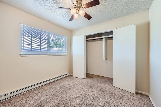 Empty bedroom with carpet, window, and large closet.