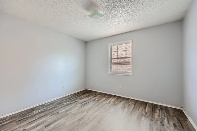Empty bedroom with light gray walls and wood-look laminate flooring.