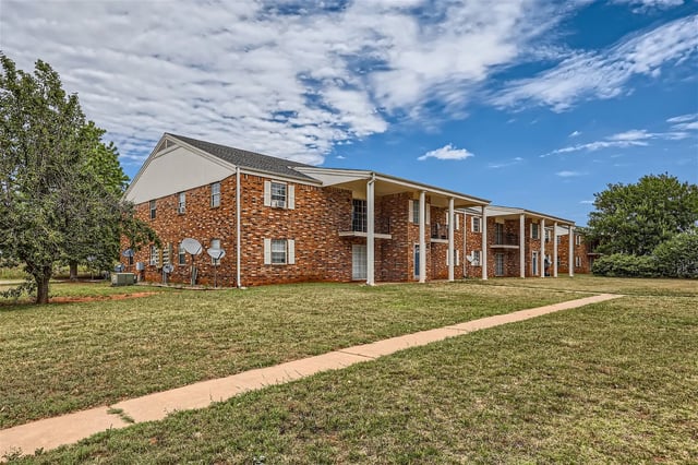 Exterior of a brick apartment building with a covered walkway and balconies.