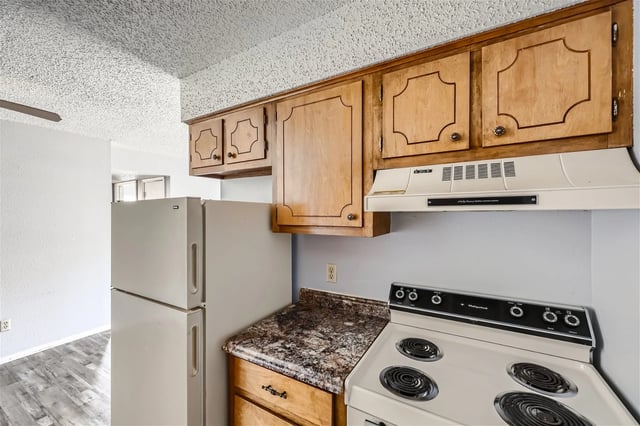 Kitchen with wood cabinets, a white refrigerator, and a white stove.